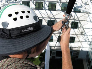Da Brim PRO Tech Construction Helmet Visor Brim in gray at work. Man performing rigging duties at height while working and wearing the Da Brim PRO Tech Construction Helmet Visor Brim in gray.