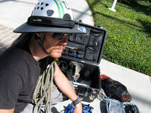 Load image into Gallery viewer, Professional climber wearing the Da Brim PRO Tech Construction Helmet Visor Brim in gray. Pictured in front of toolbox at a job site.