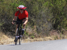 Load image into Gallery viewer, Riding a road bike with Da Brim Cycling Classic. Man on bike coming from downhill.