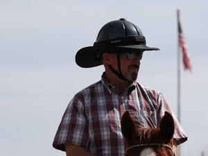 Male rider on horse with American flag in background. Rider is wearing the Da Brim Equestrian Petite Helmet Brim Visor in black.