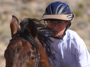 Close up photo of a woman riding her horse. She is wearing the Da Brim Rezzo helmet visor in tan.