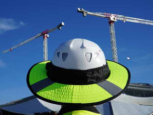 Da Brim PRO Tech Lite Construction helmet visor brim in fluorescent yellow with reflective on the job site. Rear view of brim pictured against background of a building and 2 cranes.