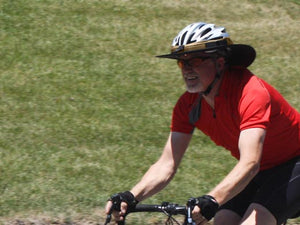 Road biker wearing the Da Brim Sporty Cycling Helmet Visor Brim in tan.